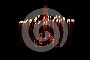 Many candles burning at night on the black background in church. Candle flame set isolated in black background. Group of burning