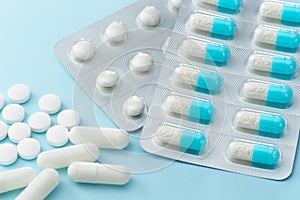 Many capsule medicines and pills on blue background.