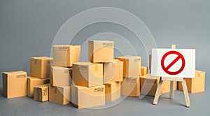 Many cardboard boxes and a sign stand with red symbol NO. Embargo, trade wars. Inability to sell products, ban on the import