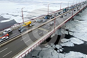 Many cars drive over river bridge in winter. Traffic jam, air pollution, smog on highway, road. Bridge in Dnipro Ukraine, drone