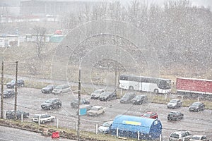 Many cars are parked in the parking lot during the snowfall