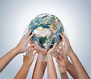 Many children hands holding planet earth isolated on blue background