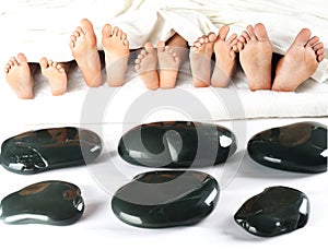 many children\'s feet peek out from under the blanket against the background of smooth stones. relaxation holiday