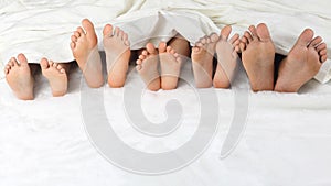 Many children`s feet peeking from under the blanket