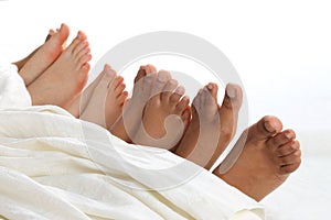 Many children`s feet peeking from under the blanket