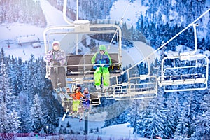 Many children on ski chairlift over snowy forest