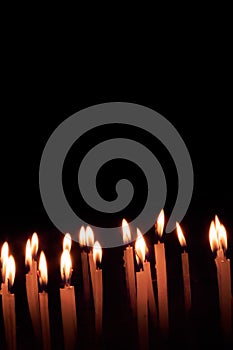 Many christmas candles burning at night on the black background