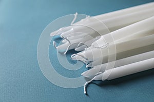 Many church wax candles on light blue background, closeup. Space for text