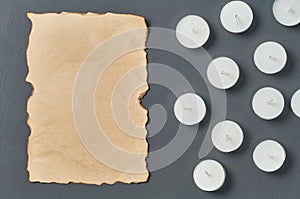 Many circle candles and ancient burnt paper sheet on dark concrete