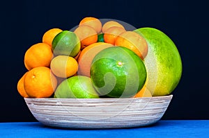 Many citruses on a plate. Oranges, tangerines, limes, pomelo, grapefruits.