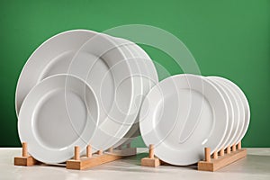 Many clean plates on white table against green background