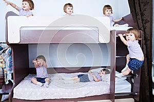 Many clone baby girls on bund bed in child room in domestic life. identical child crowd. Kid with different emotion