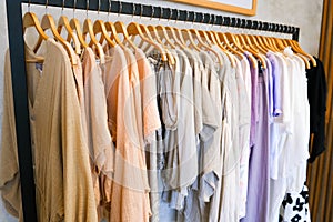 many cloths on hangers in retail fashion shop.