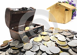 Many coins and mini Treasure Chest. Concept Save money for home lone on white background. Many type of coins and blur wooden