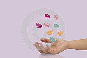 Many color wooden heart ball on woman hand isolated on purple background