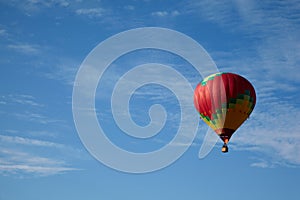 Many-colored hot air balloon with people fly