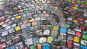 Many colored painted cobble stone pavement in after rain