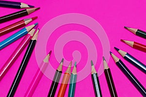 Many colored pencils lie on a pink background. Copy spase. The concept of back to school, the educational process, study at school