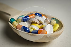 Many colored tablets in a wooden spoon on a table