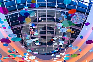 Many colorful abstract decorations hang under a huge glass ceiling in the mall