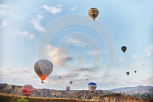 Many colorful balloons take off into the sky at dawn. All the sky in big beautiful balloons. Fabulous landscapes of the mountains