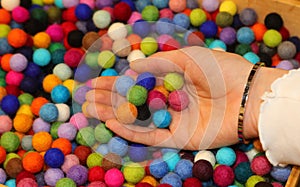 many colorful balls made of boiled wool on sale in the hand of girl  ideal for making personalized creations