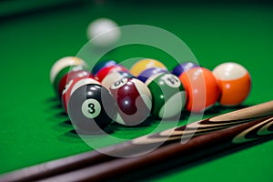 Many colorful billiard balls and cue on green table