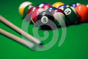 Many colorful billiard balls and cue on green table