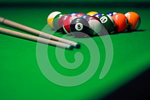 Many colorful billiard balls and cue on green table