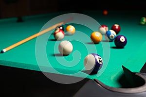 Many colorful billiard balls and cue on green table, space for text