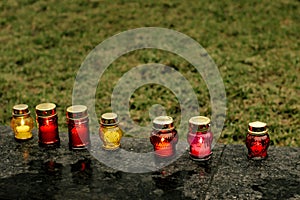 many colorful candles with light burning in city center on marble stone, memorial day and sad bereavement moment photo