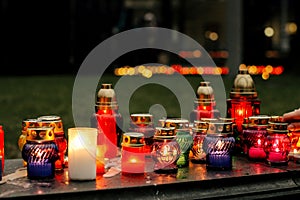 many colorful candles with light burning in city center on marble stone, memorial day and sad bereavement moment photo