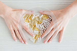 Many colorful capsules of tablets, vitamins, dietary supplements in hand on a white table close-up