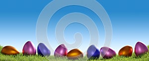 Colorful Easter eggs in a row on a grass background, Easter concept