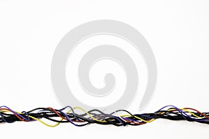 Many colorful electrical cord cables twist together into single frame line on white background. Top view, copy space