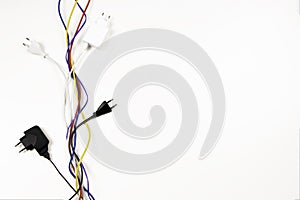 Many colorful electrical cord wires cables cord with plugs twist on white background. Top view, copy space