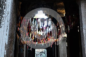 Many colorful flags under the ceiling of the old temple. Garlands in a buddhist temple