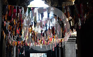 Many colorful flags under the ceiling of the old temple. Garlands in a buddhist temple