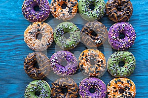 Many colorful fun donuts with and sugar eyes for Halloween, full frame, flat lay