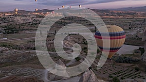 Many colorful hot air balloons flight above mountains - panorama of Cappadocia at sunrise.