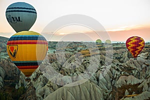 Many colorful hot air balloons flight above mountains - panorama of Cappadocia at sunrise. Wide landscape of Goreme valley