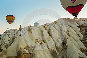 Many colorful hot air balloons flight above mountains - panorama of Cappadocia at sunrise. Wide landscape of Goreme valley