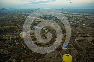 Many colorful hot air balloons flight above mountains - panorama of Cappadocia at sunrise. Wide landscape of Goreme valley