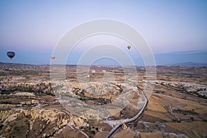 Many colorful hot air balloons flight above mountains - panorama of Cappadocia at sunrise. Wide landscape of Goreme valley in