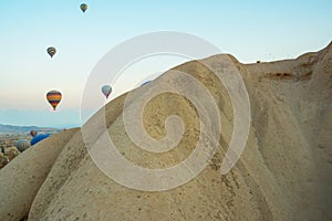 Many colorful hot air balloons flight above mountains - panorama of Cappadocia at sunrise. Wide landscape of Goreme valley