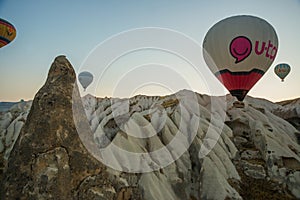 Many colorful hot air balloons flight above mountains - panorama of Cappadocia at sunrise. Wide landscape of Goreme valley