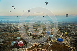 Many colorful hot air balloons flight above mountains - panorama of Cappadocia at sunrise. Wide landscape of Goreme valley