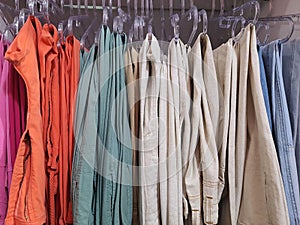 Many colorful jeans are hanging on a hanger. Close-up of jeans hanging in the store. Jeans or denim pants hanging on a hanger