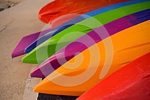 Many colorful kayaks lie on the ocean shore