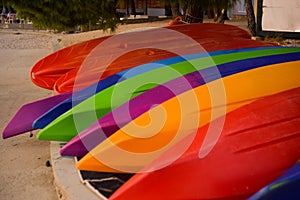 Many colorful kayaks lie on the ocean shore
